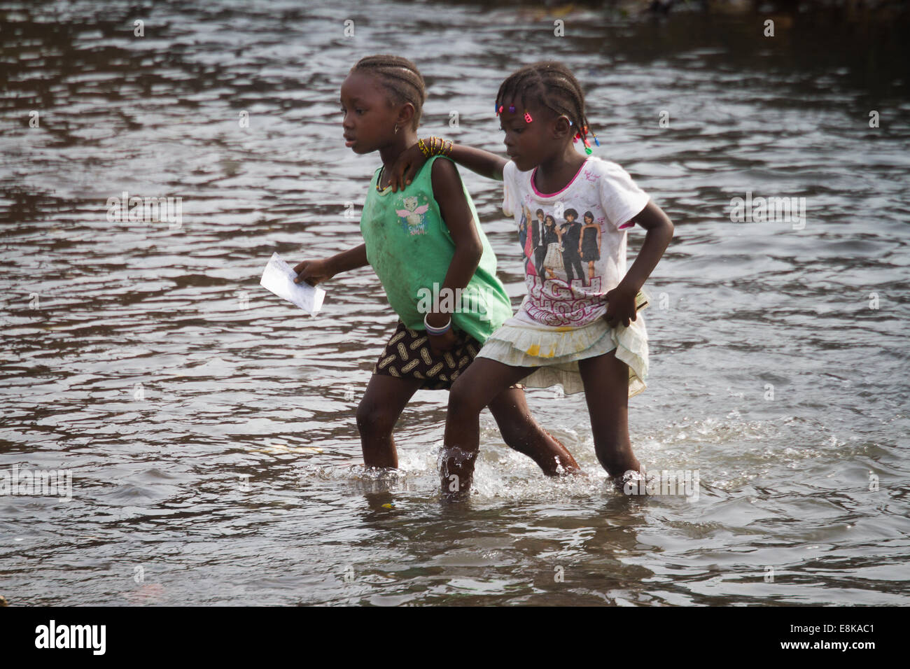 Girls crossing dirty stream, Kroo Bay, Freetown, Sierra Leone. Photo