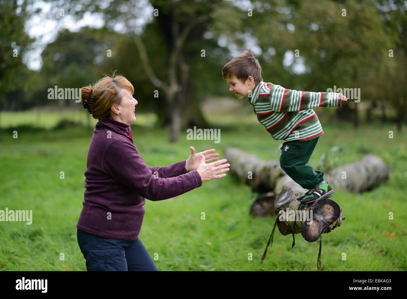 Child children boy having outdoor fun with grandmother jumping into the arms trust trusting Uk Stock Photo