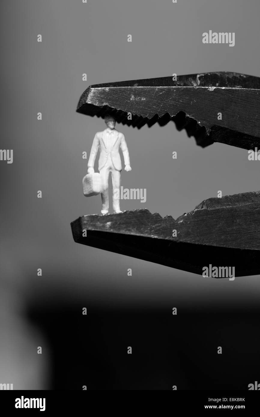 Small figure of a business man clamped into pliers Stock Photo Alamy