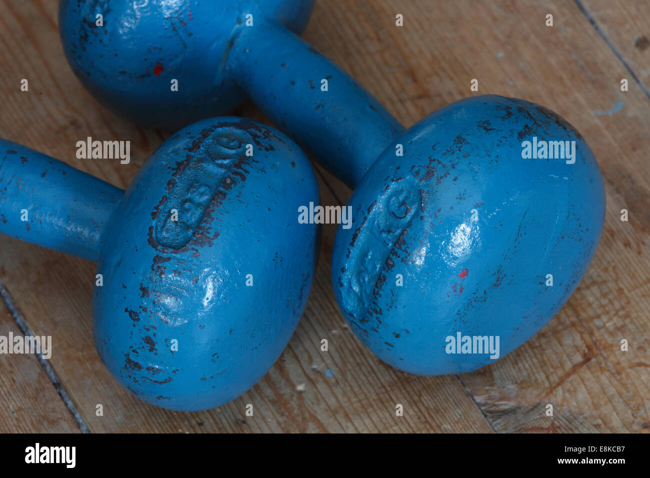 Blue dumb bells lying on a wooden floor. Stock Photo