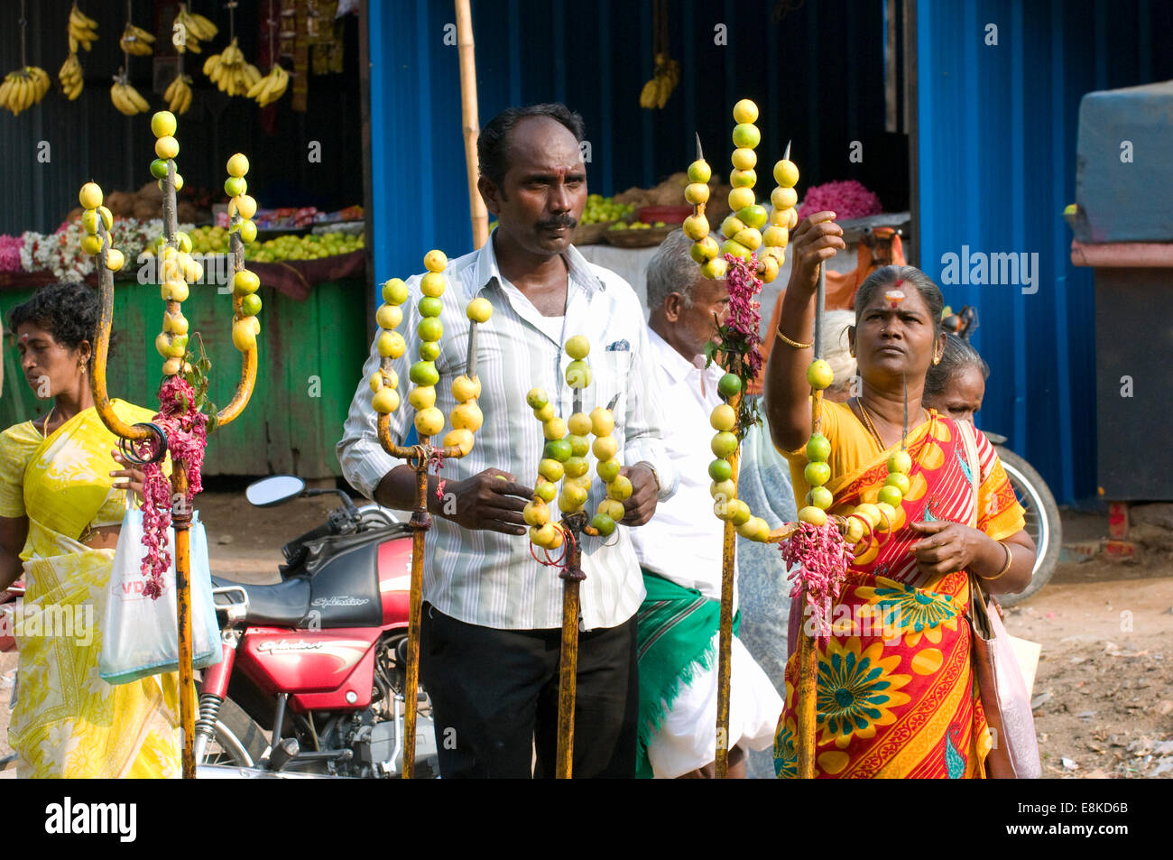 Hindu devotees offering prayers, salutations & offerings of limes pierced onto sacred trident weapons outside the Goddess Durga Stock Photo