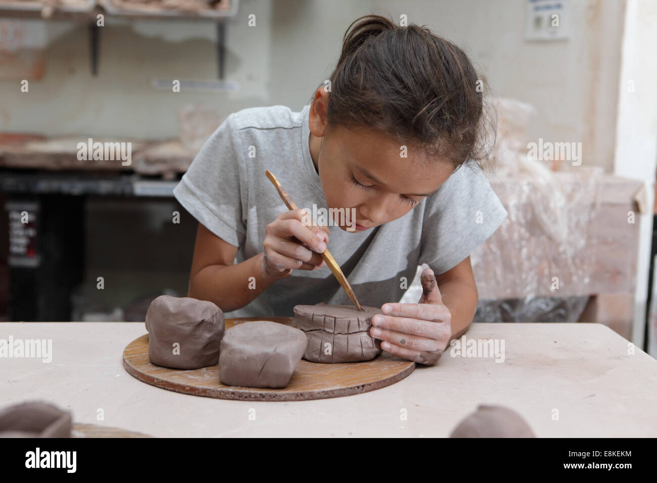 Young girl takes part in a pottery class learning how to decorate clay