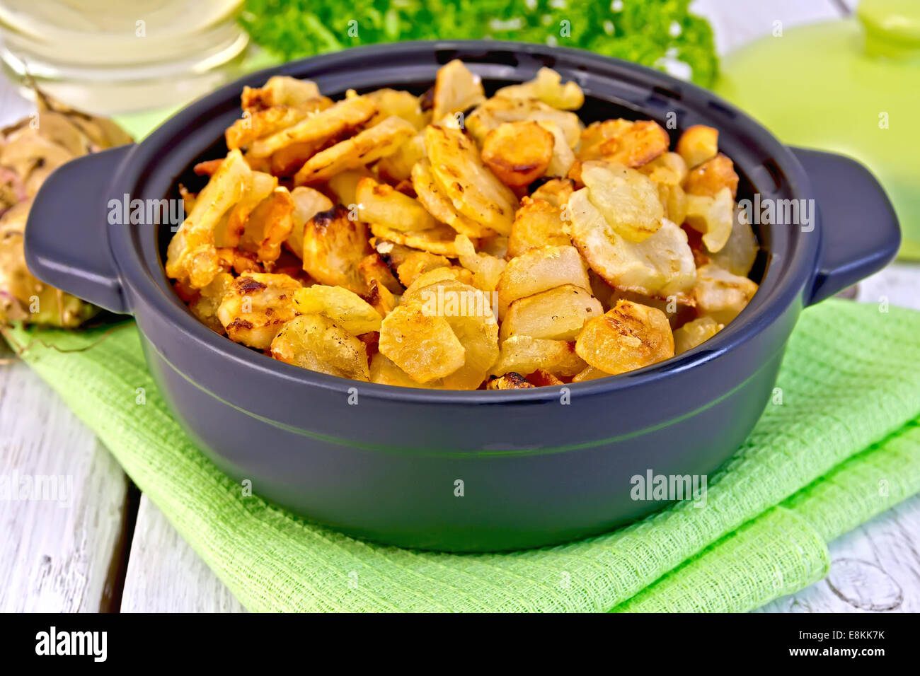 Jerusalem artichokes roasted in a roasting pan, fresh tubers on a napkin, parsley, vegetable oil on a background of white wooden Stock Photo