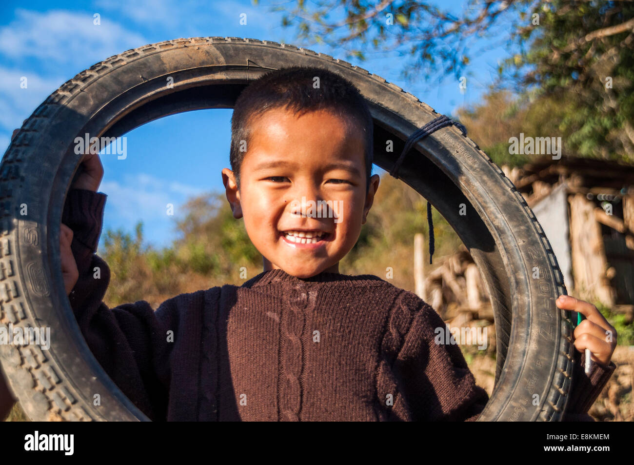 Smiling boy from the Lahu people, hill tribe, ethnic minority, plays with a motorcycle tyre, Mae Hong Song Province Stock Photo