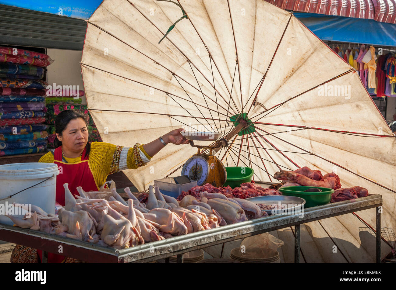 Saleswoman on the market, meat stand with large parasol, Pang Mapha, Mae Hong Song province, Northern Thailand, Thailand Stock Photo