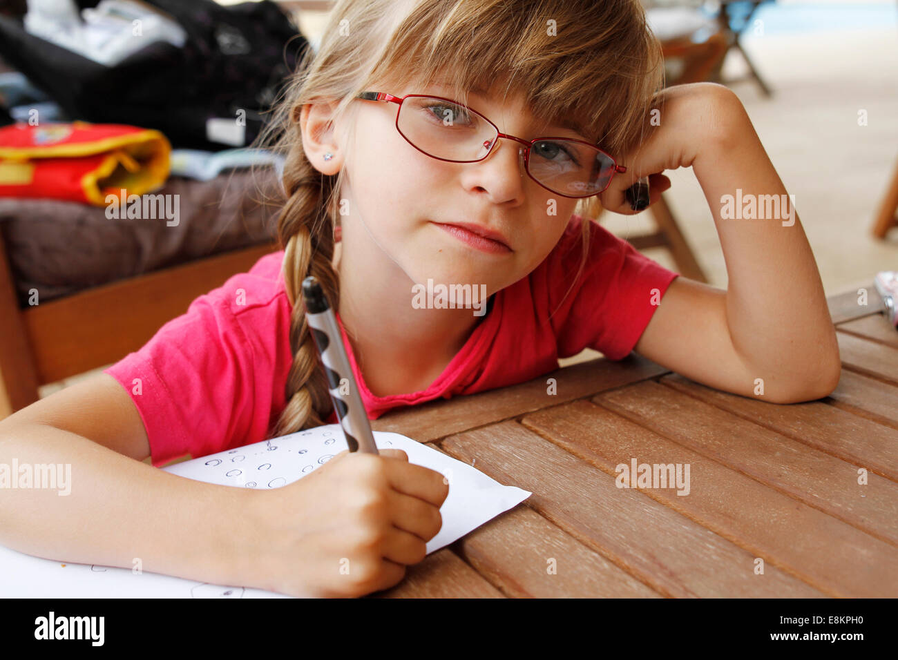 A 6-year old girl practising writing during the holidays. Stock Photo