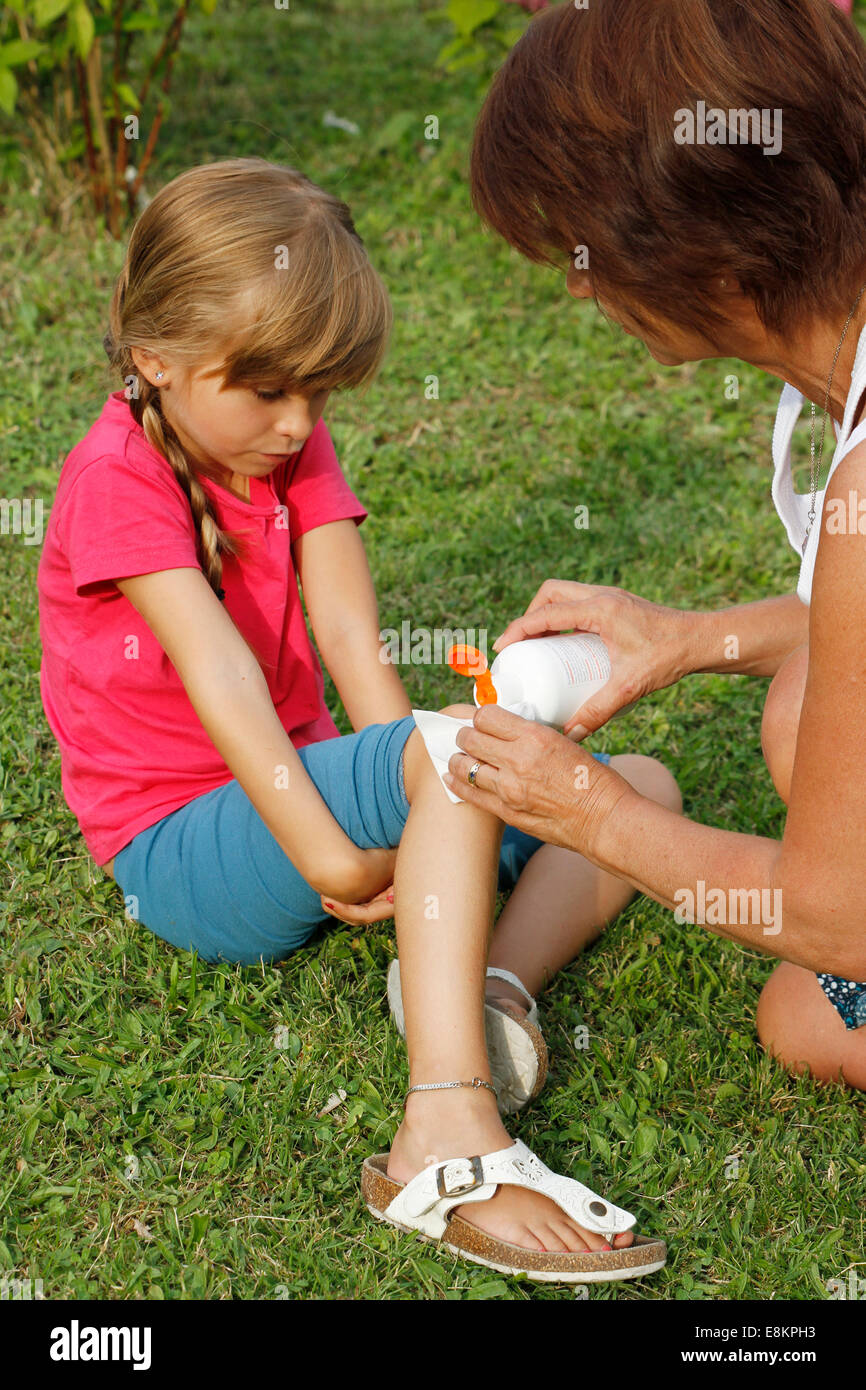 A mother cleaning a graze on her 6-year old daughter's knee. Stock Photo