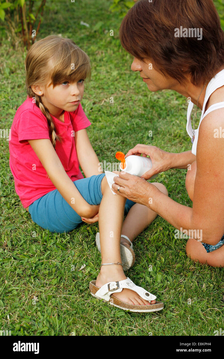A mother cleaning a graze on her 6-year old daughter's knee. Stock Photo