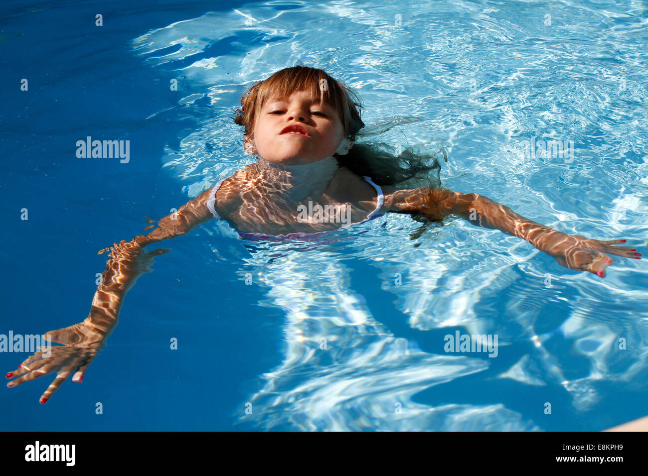 A 6-year old girl swimming for the first time without armbands in a  swimming pool Stock Photo - Alamy