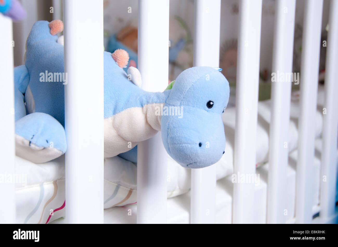 Toy dinosaur hanging out of babies crib Stock Photo Alamy