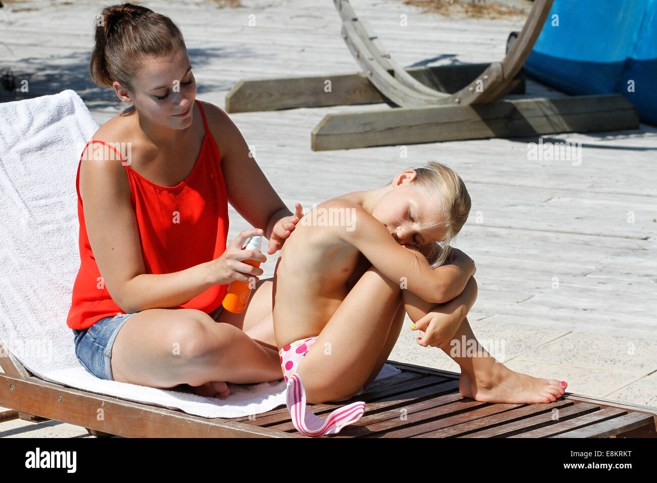 A young woman putting sun cream on a young girl's back. Stock Photo