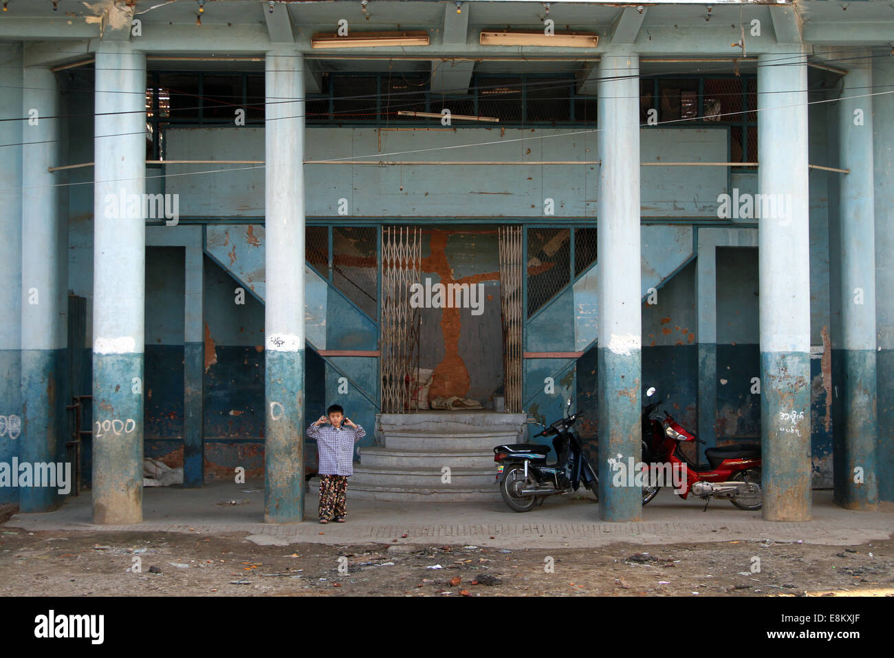 A child plays in the porch of an abandoned building in central Kengtung, Burma (Myanmar) on Saturday 7 January 2012 Stock Photo