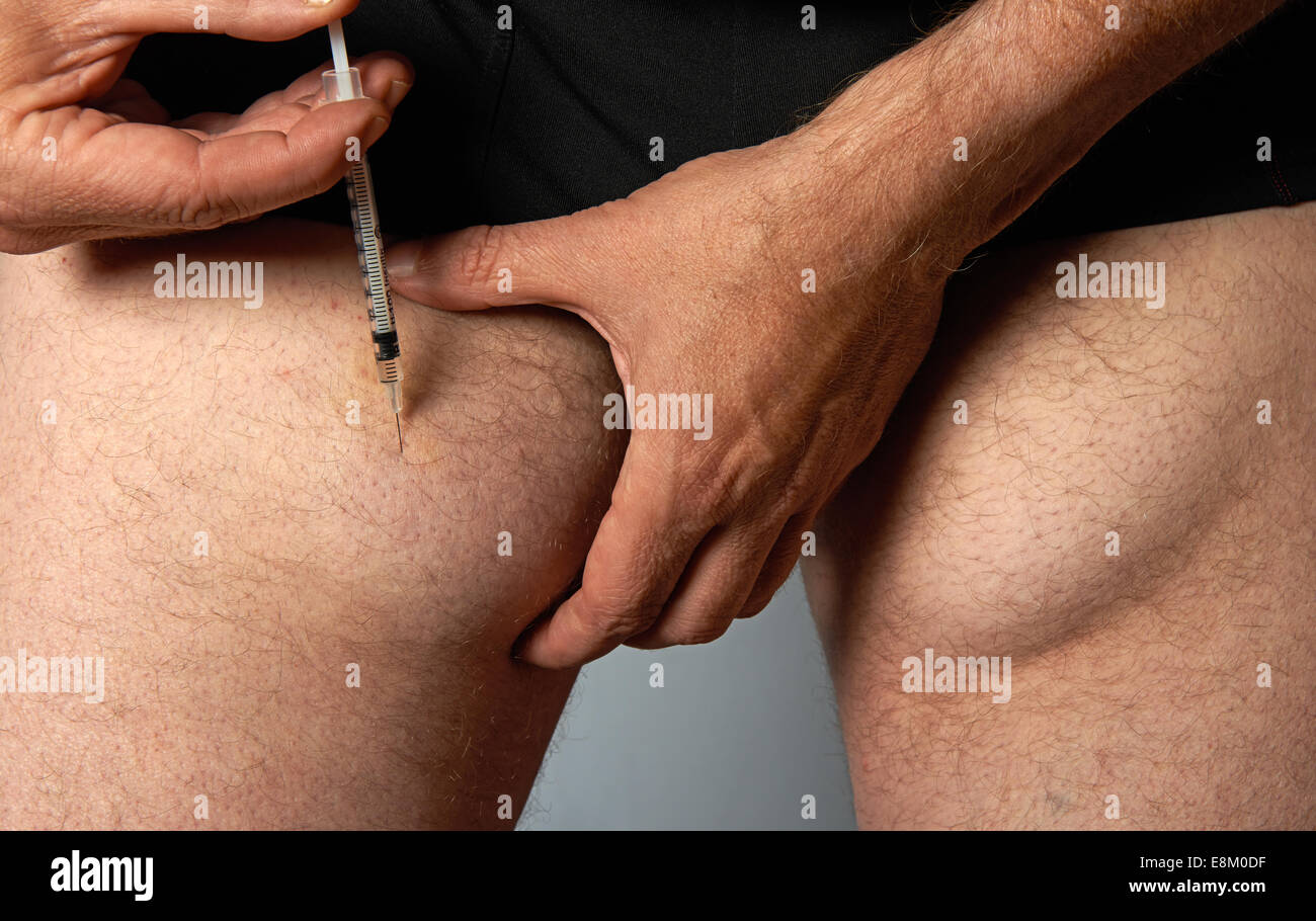 Diabetic man injecting insulin into his leg which over the years has caused lumps under the skin Stock Photo