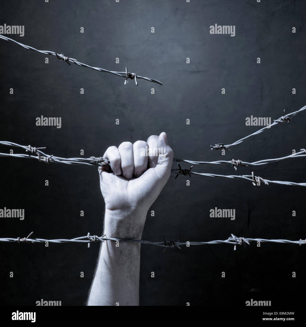 hand behind barbed wire with dark background Stock Photo