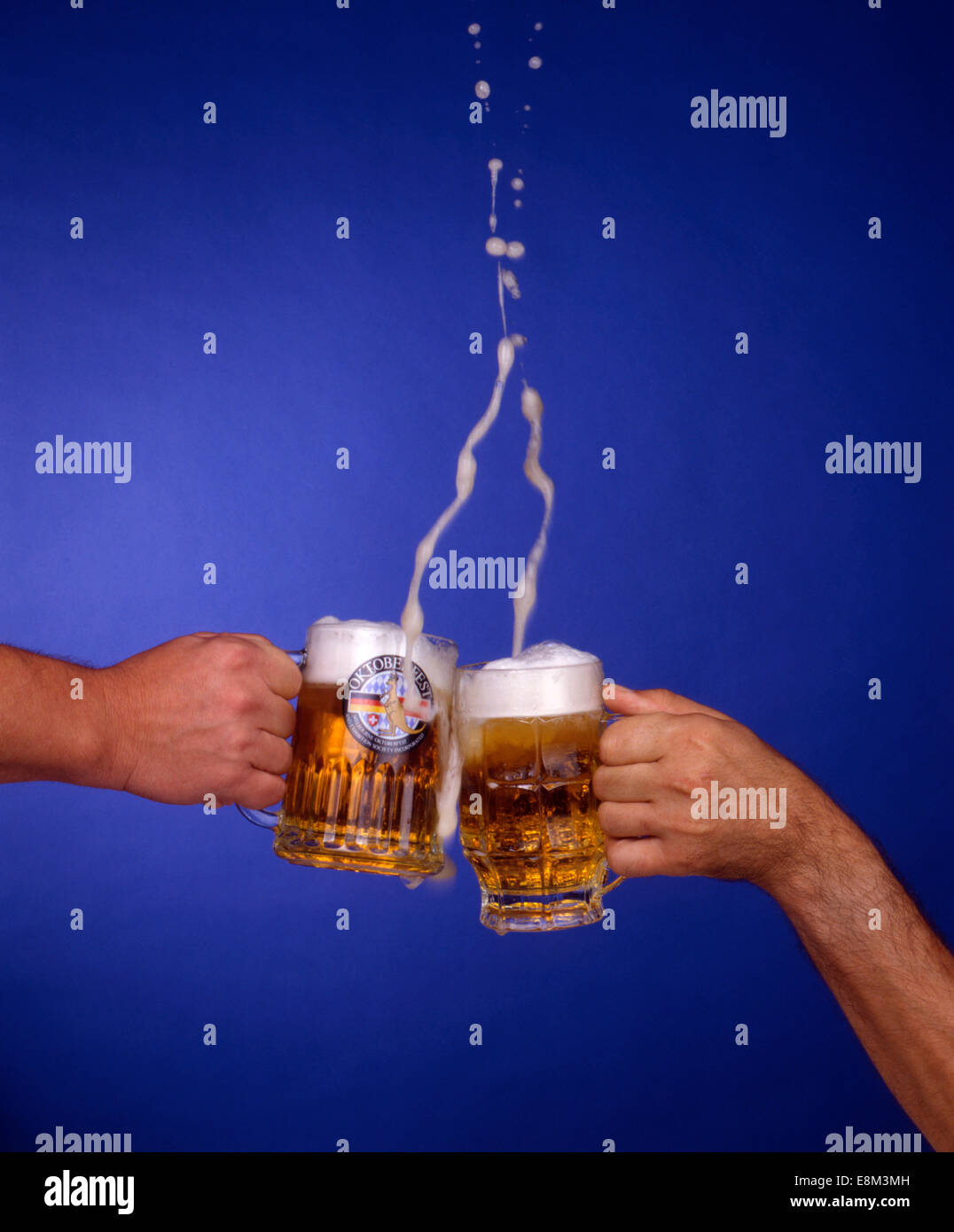 zwei Hände mit Biergläsern stossen an, Symbolbild, Bierhumpen, Oktoberfest Melbourne, Bier, Bierschaum spritzt aus den Gläsern, Stock Photo