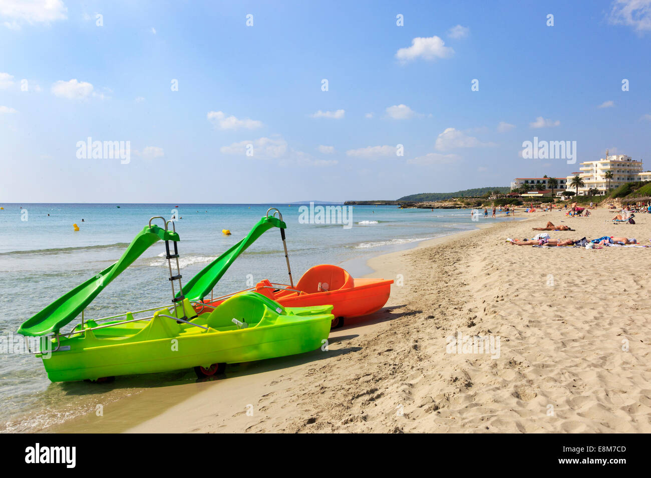 Beach at Sant Tomas with tourists sunbathing and two plastic pedalos, Menorca, Balearic Islands, Spain Stock Photo