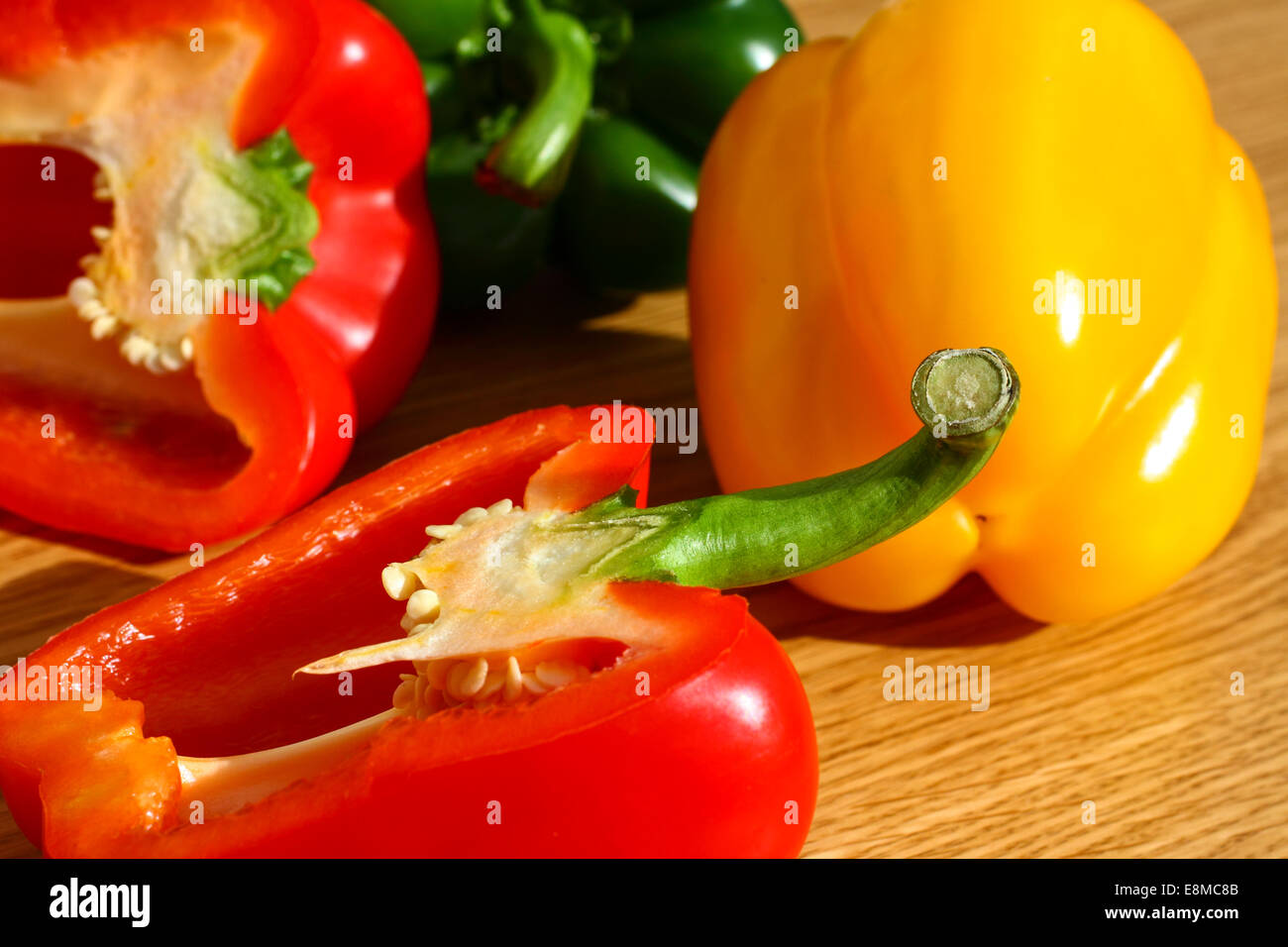 Red, green and yellow peppers on a chopping board Stock Photo - Alamy