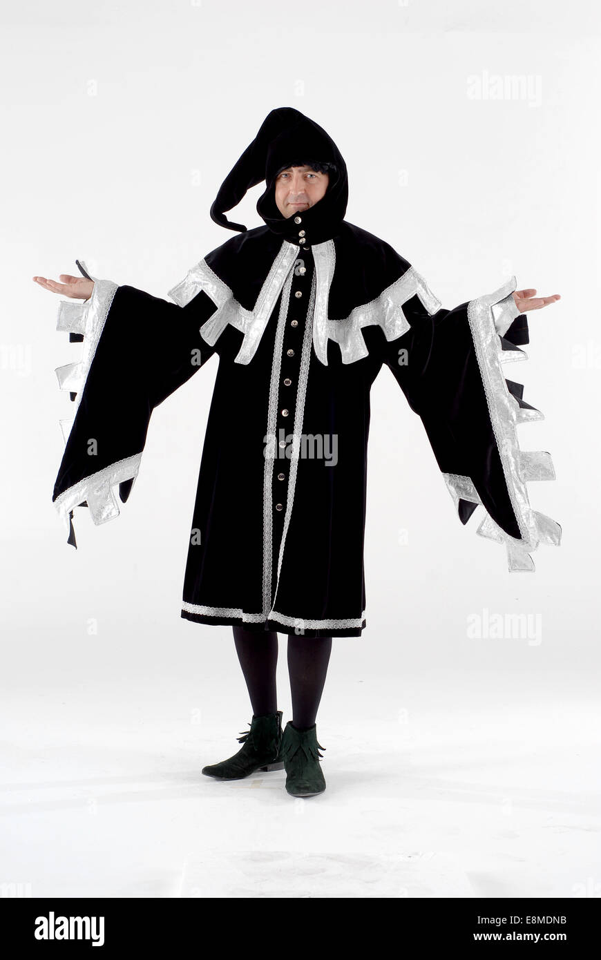 Man dressed in fancy dress comedy costume as a court jester in full historical costume in a white photography. Stock Photo