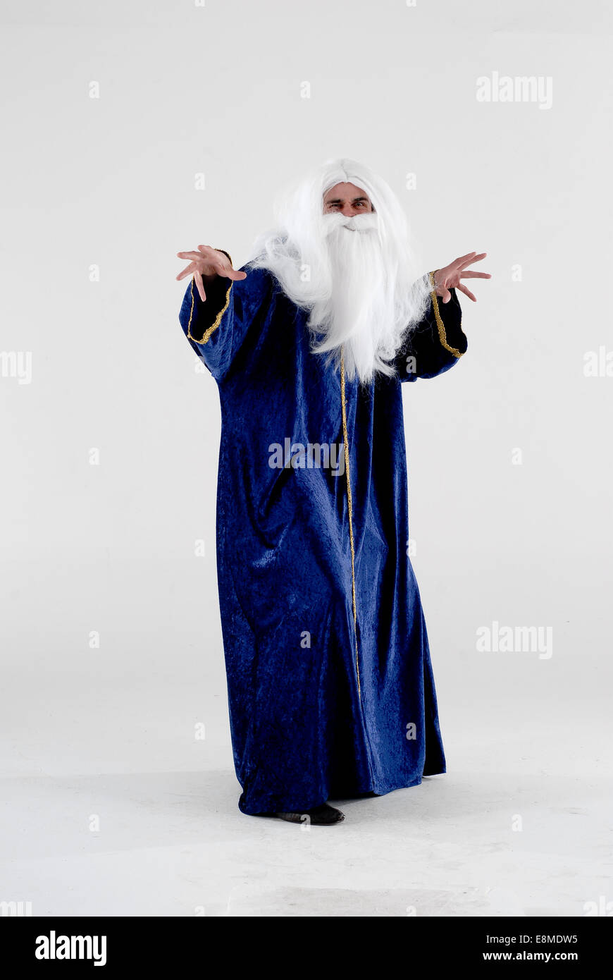 man in fancy dress comedy costume as a god like figure or a wizard with white long hair, beard and blue gown Stock Photo