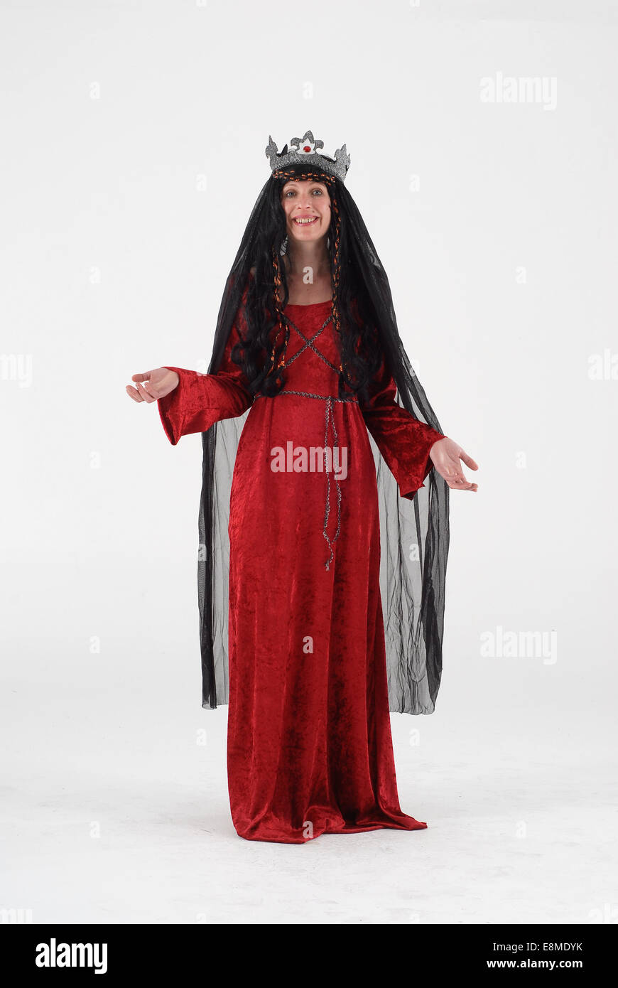 Woman in fancy dress comedy costume in a medieval queen historical outfit with crown, black veil and red dress Stock Photo