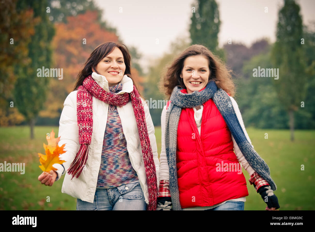 Two young woman walking in autumn park Stock Photo - Alamy