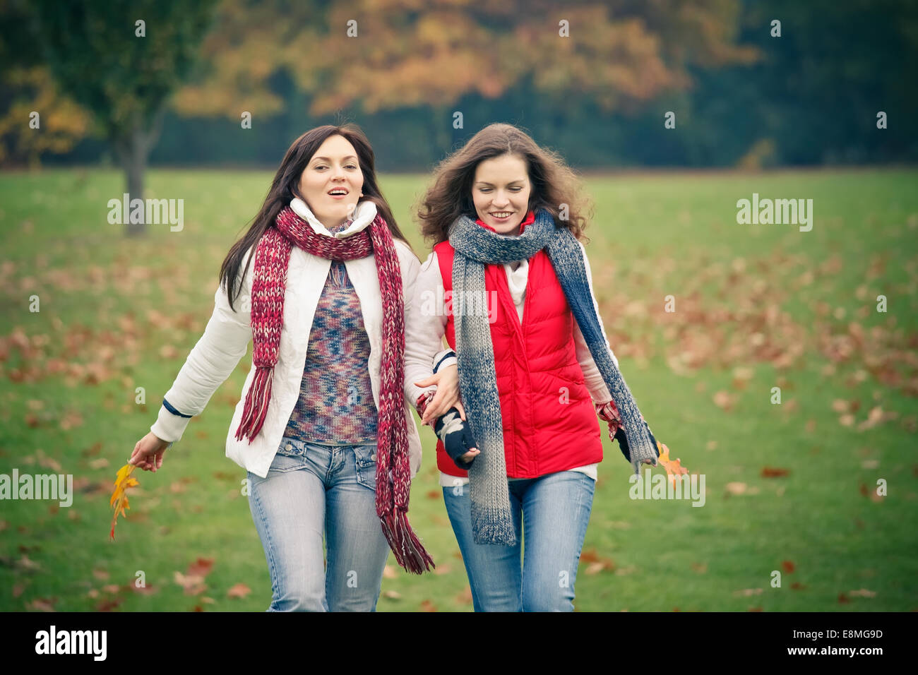 Two young woman walking in autumn park Stock Photo - Alamy