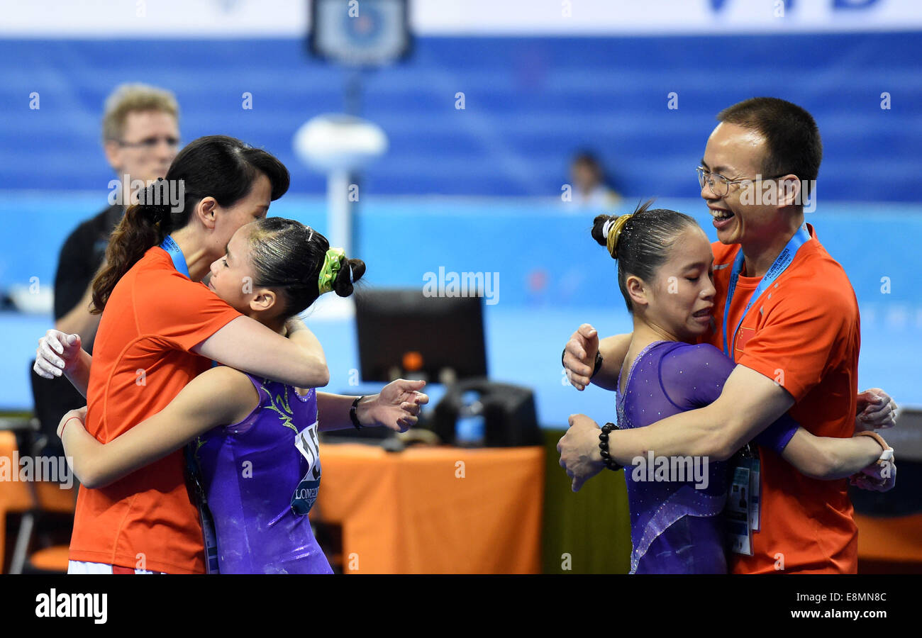 Nanning, China's Guangxi Zhuang Autonomous Region. 11th Oct, 2014. Chinese gymnasts Yao Jinnan (2nd R) and Huang Huidan (2nd L) hugs their coaches after their uneven bars performances during the women's individual apparatus finals of the 45th Gymnastics World Championships in Nanning, capital of south China's Guangxi Zhuang Autonomous Region, Oct. 11, 2014. Yao Jinnan won the gold medal in the women's uneven bars final with 15.633 points. Huang Huidan won the silver medal with 15.566 points. Credit:  Zhou Hua/Xinhua/Alamy Live News Stock Photo