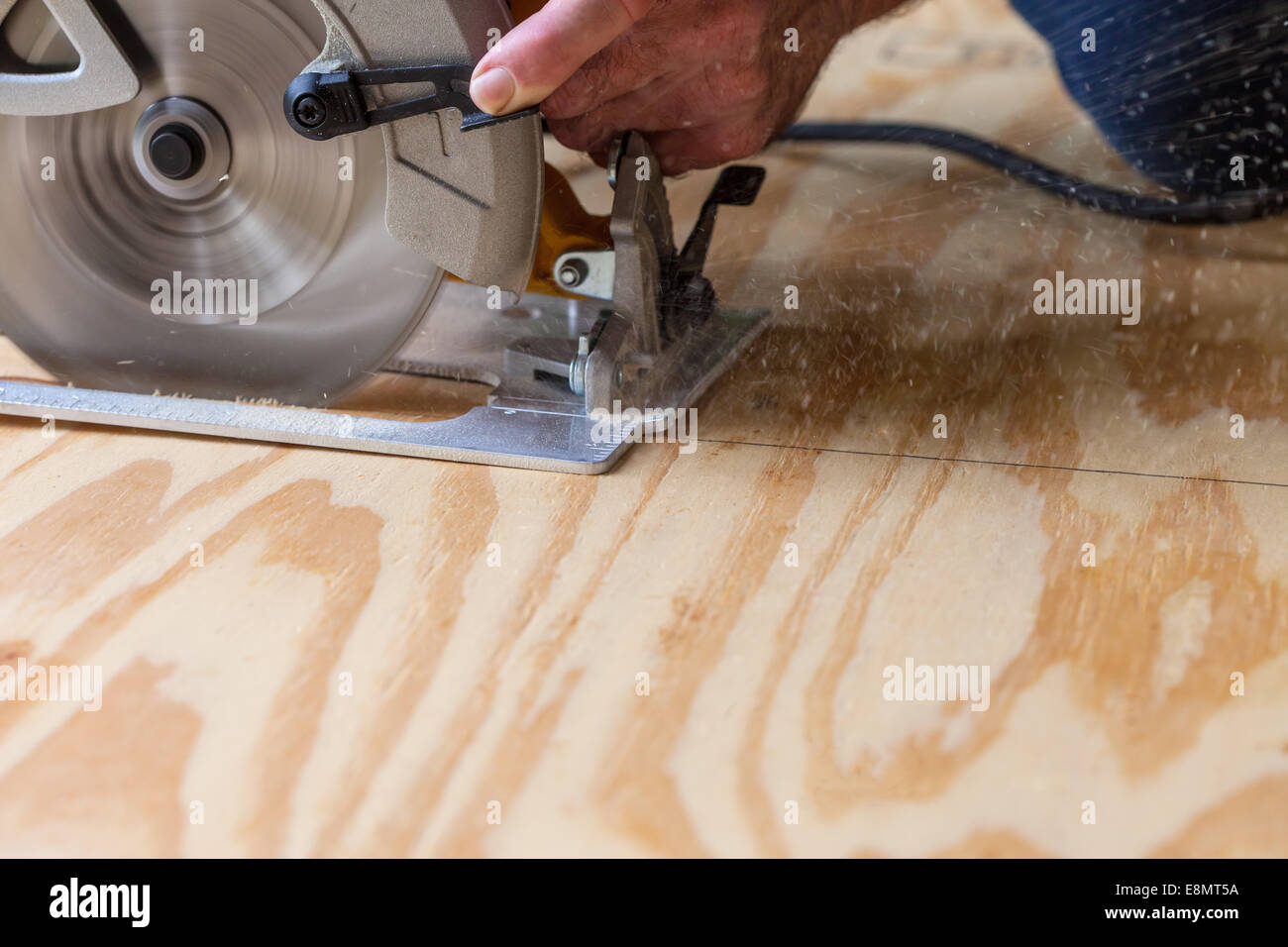 Man using a circular saw to cut plywood Stock Photo