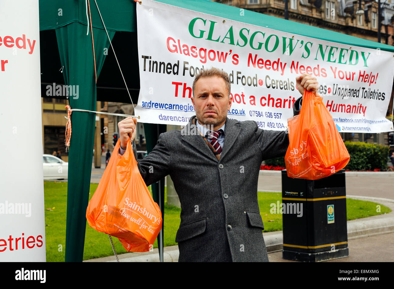 Glasgow, Scotland. 11th Oct, 2014. Andrew Carnegie, aged 45, from Tollcross in Glasgow, who set up the Foodbank charity 'Glasgow's Needy' set up a stall in George Square, Glasgow city centre, outside the City Chambers, with the intention of collecting contributions and also drawing attention to social inequality and the needs of the poor. Several passers- by contributed to his charity by handing in bags of food, including Colin Boyd, aged 38. Company Director from Kilwinning. Credit:  Findlay/Alamy Live News Stock Photo