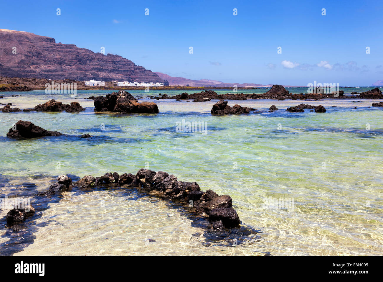 Seascape with volcanic rocks and small village in Lanzarote, Canary islands, Spain Stock Photo