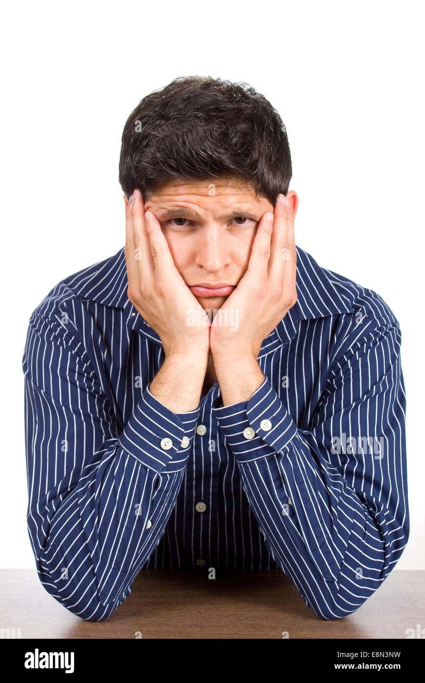 Sad looking young man looks unhappy as he stares with his face in his hands. Stock Photo