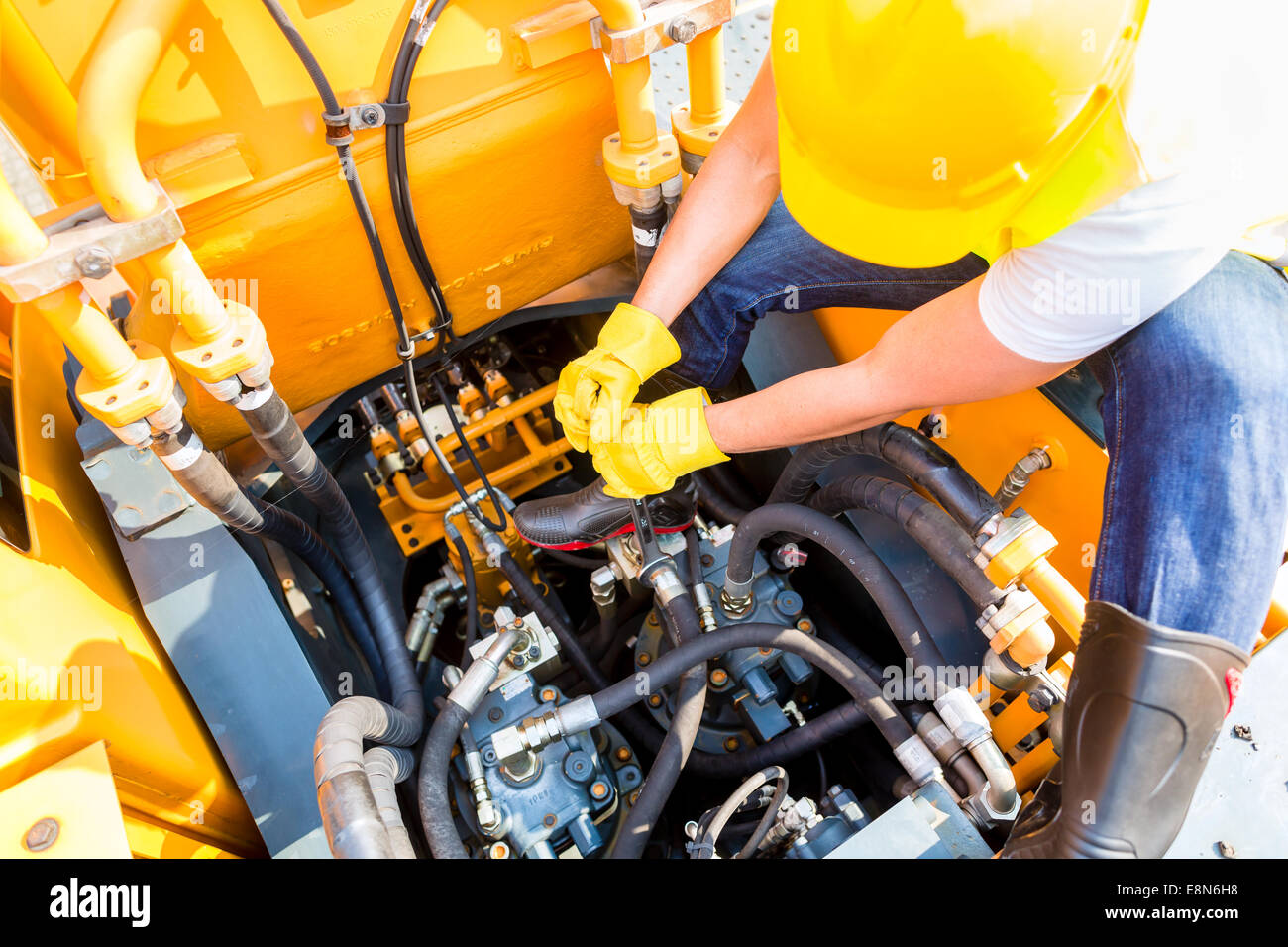 Asian motor mechanic working on construction or mining machinery in vehicle workshop Stock Photo