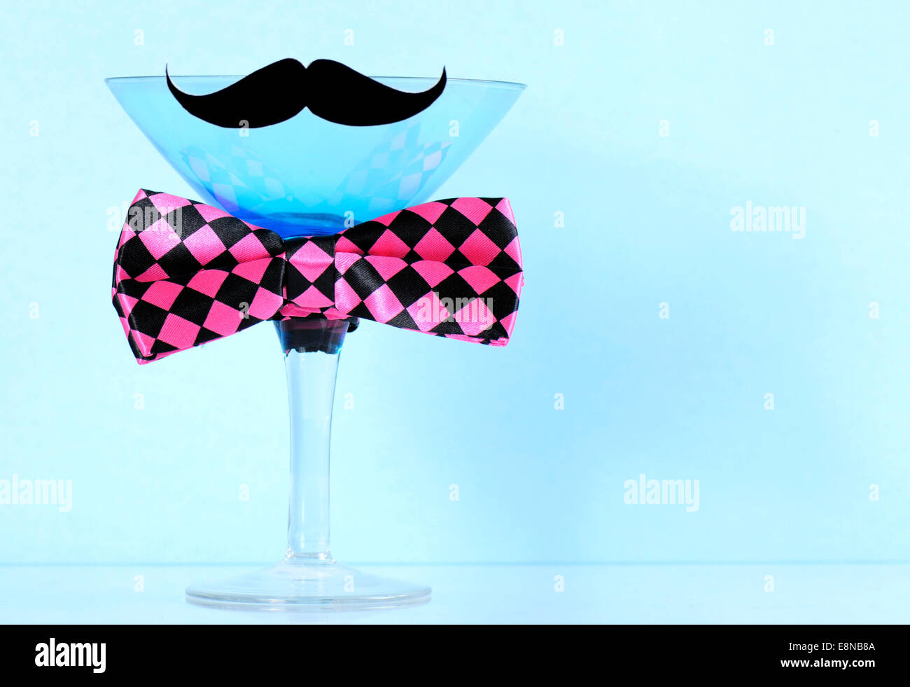 Fund raising for mens health awareness charity with mustache and bow tie on blue martini cocktail glass on blue background, with Stock Photo