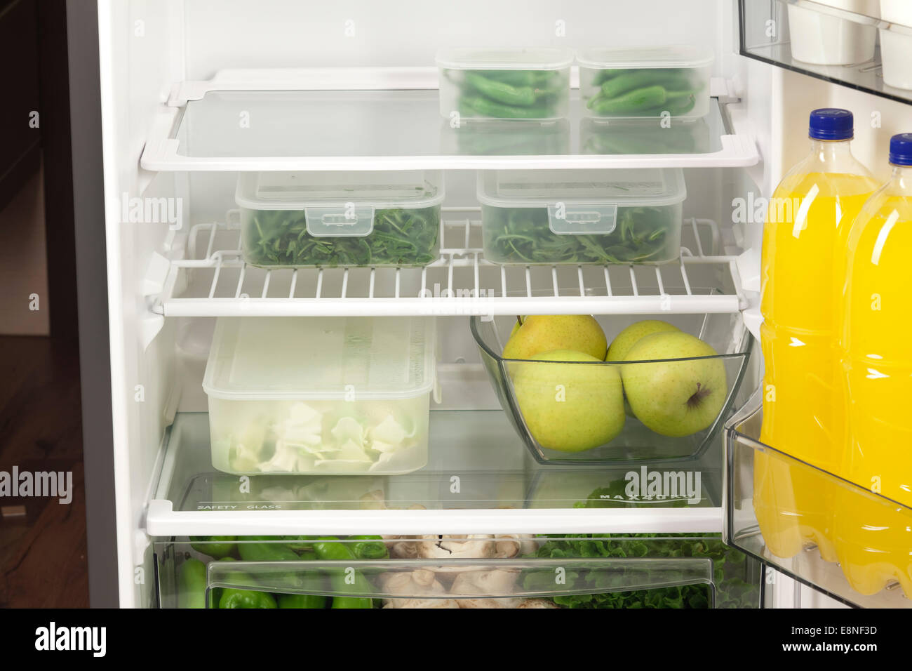 Fruits and vegetables in two containers in a modern fridge - a healthy food concept. Stock Photo