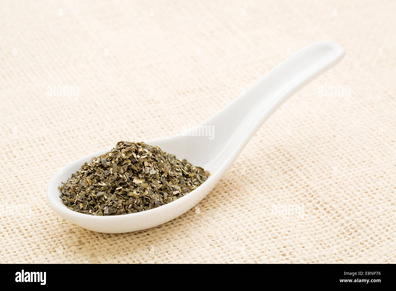 wakame seaweed on a white Chinese spoon against burlap canvas Stock Photo