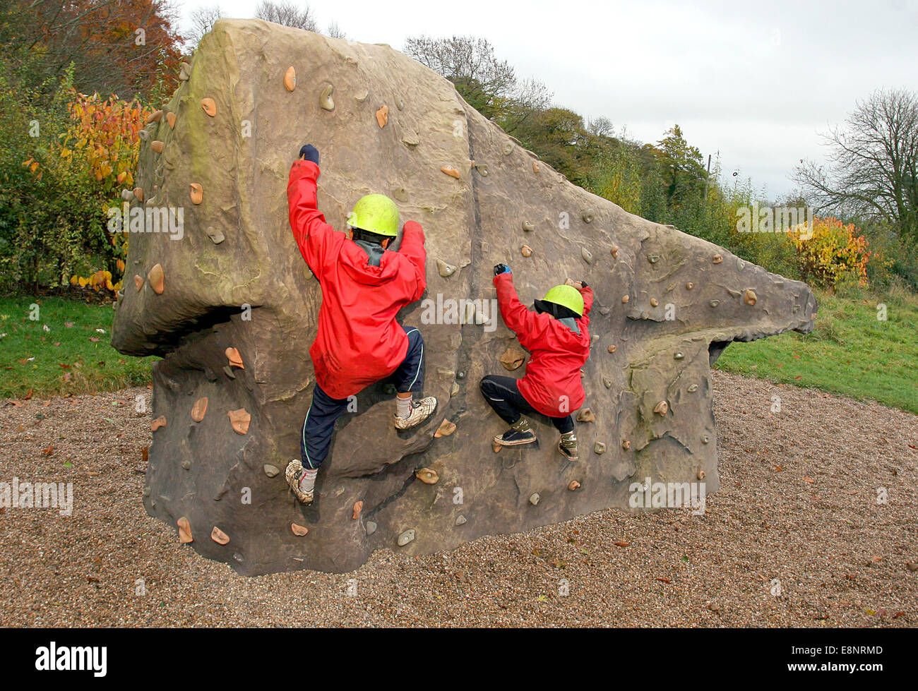 Children in helmets rock climbing outdoors on an artificial boulder Stock Photo