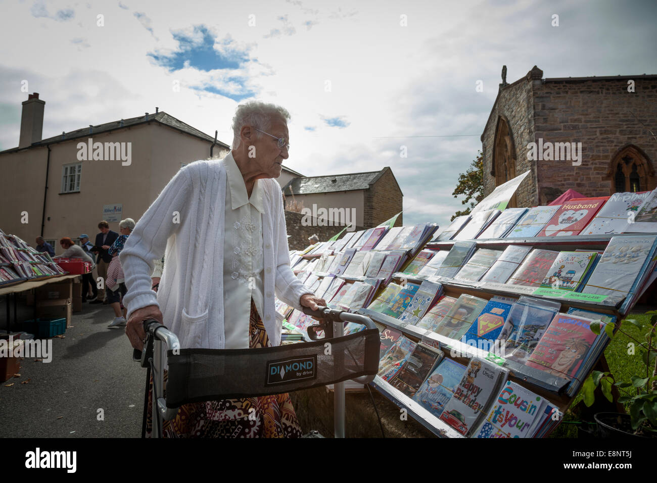 Elderly lady with a walking frame looking at a display of greetings ...