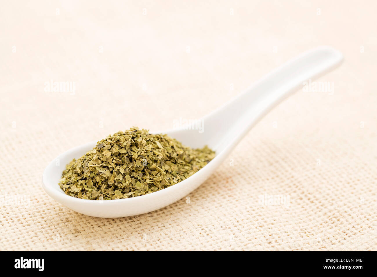 sea lettuce flakes on a white Chinese spoon against burlap canvas Stock Photo