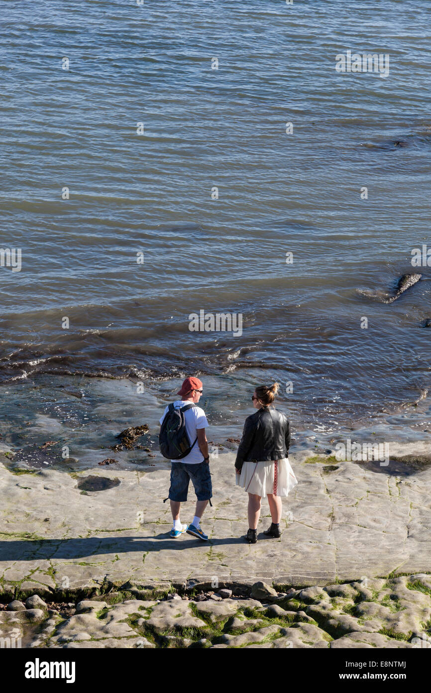 A Couple Stand And Chat On The Exposed Rock That Is Part Of The Beach Stock Photo Alamy