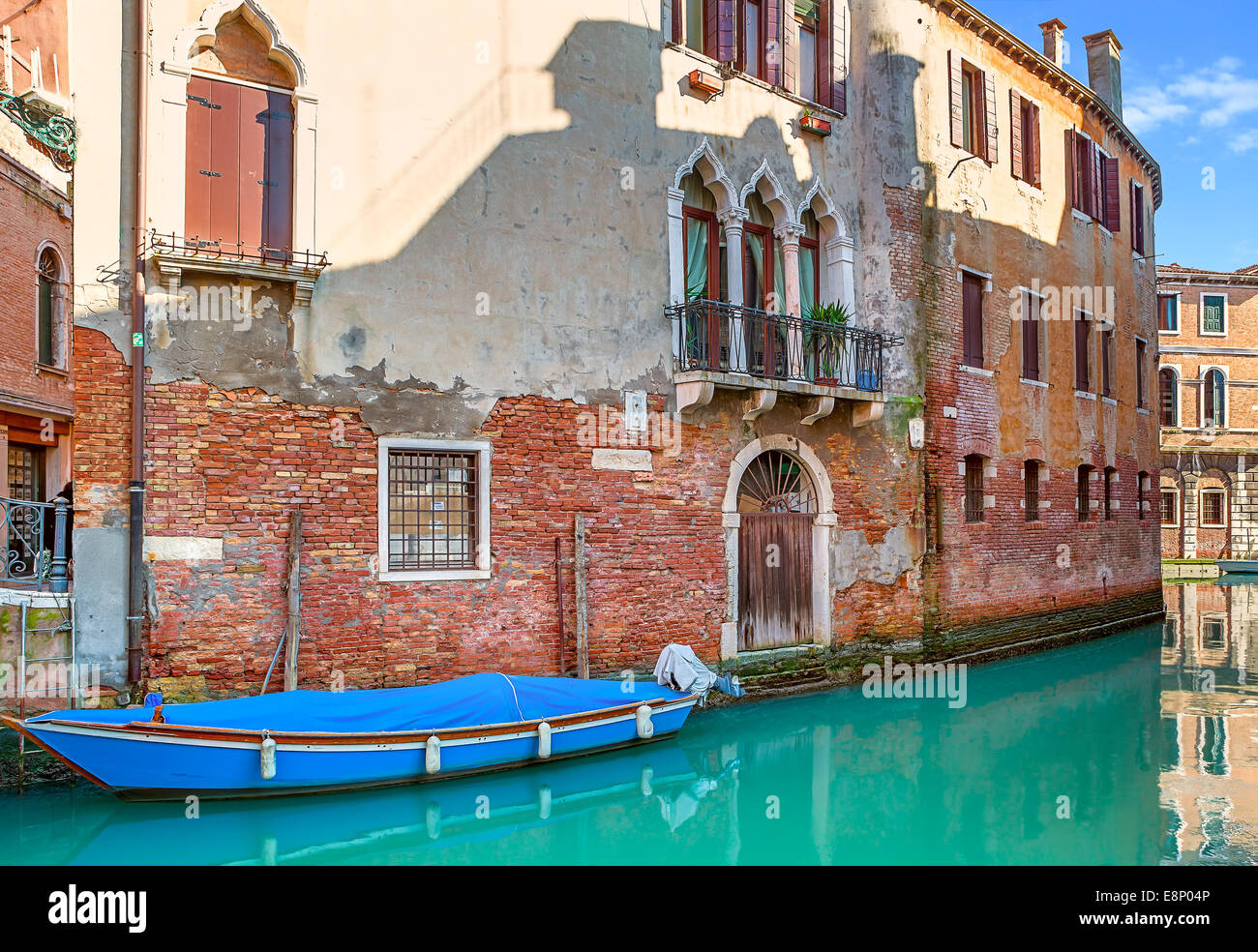 Boat on narrow canal among old brick houses in Venice, Italy. Stock Photo