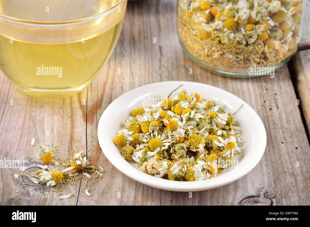 Dried camomile flowers on saucer. Chamomile tea in a transparent cup and dried camomile flowers on wooden table. Herbal tea for Stock Photo
