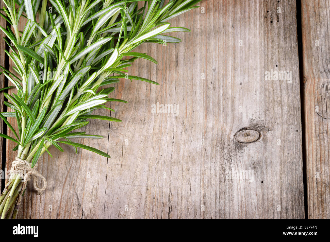 Fresh bunch of rosemary on wooden table. Aromatic evergreen herb, many culinary and medicinal uses. Stock Photo
