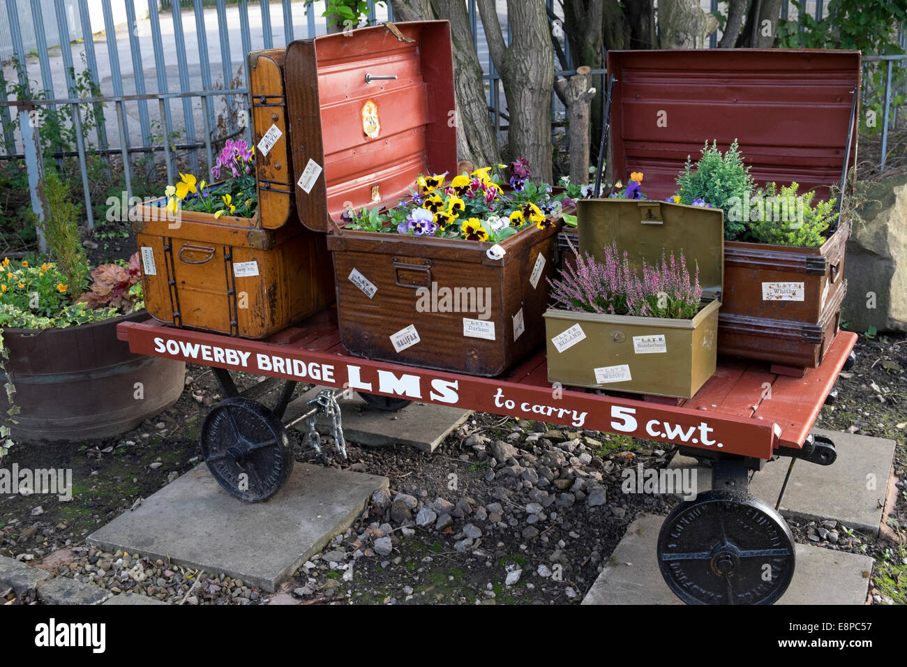 Old luggage cart with flower displays in the Brontë Garden outside Sowerby Bridge Station, West Yorkshire Stock Photo