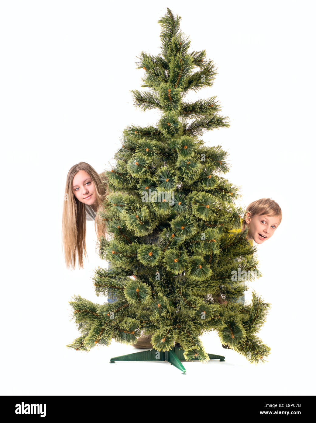 Boy and girl look out from under the Christmas tree Stock Photo