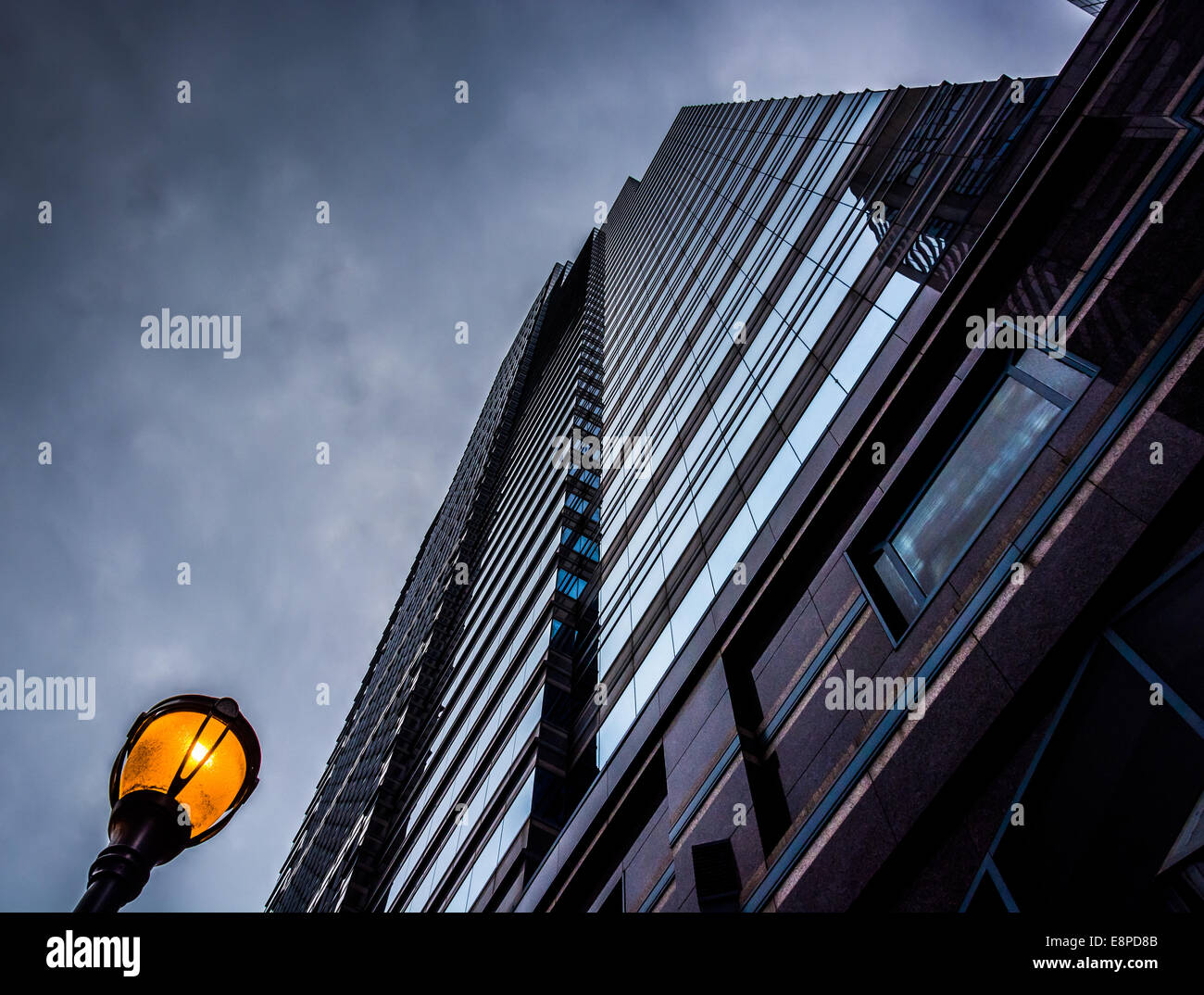 Looking up at a modern building and streetlight under a cloudy sky in ...