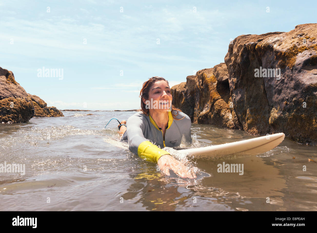 Woman swimming with surfboard to the beach. Stock Photo