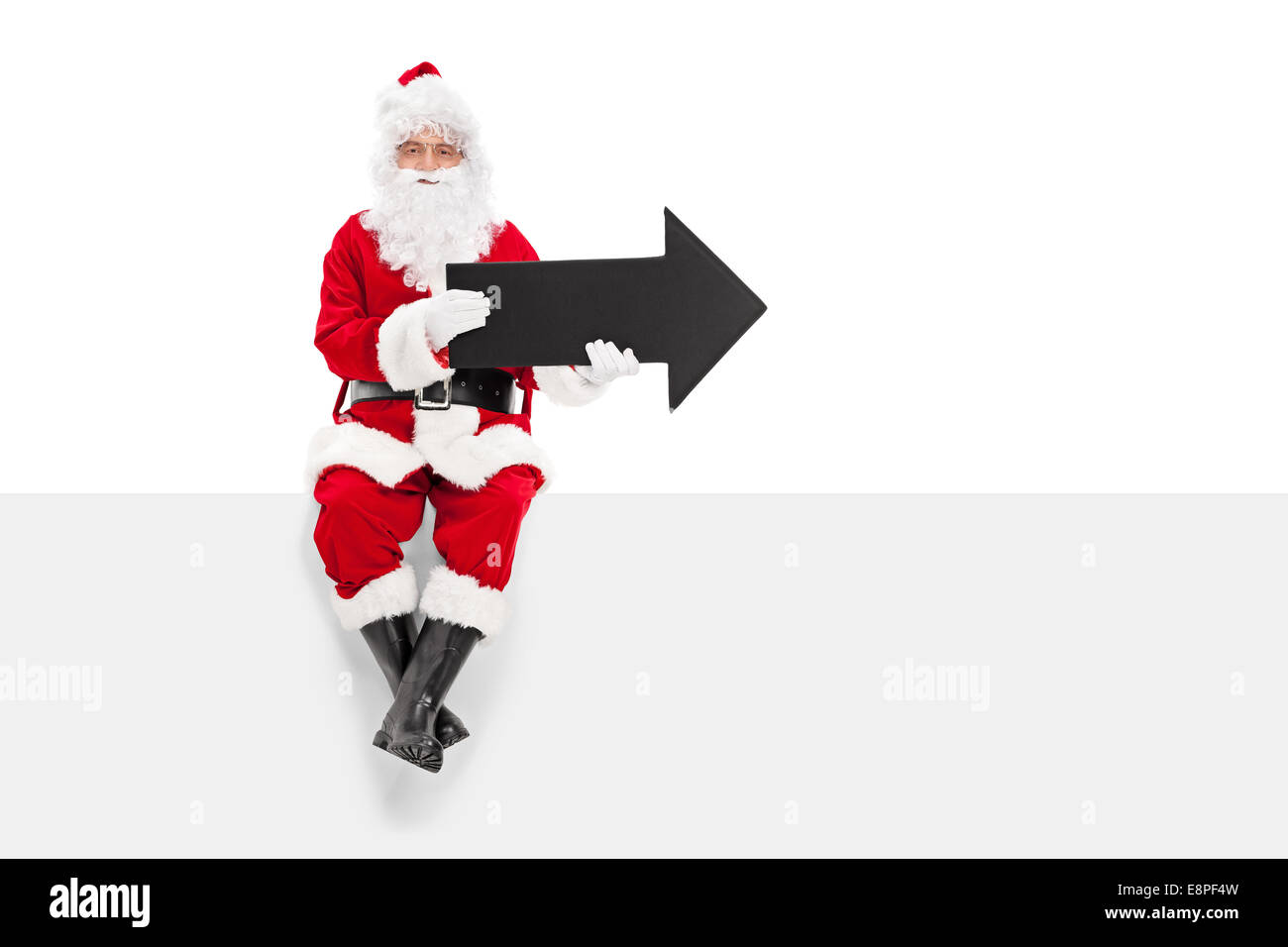 Santa Claus holding black arrow seated on a blank panel isolated on ...