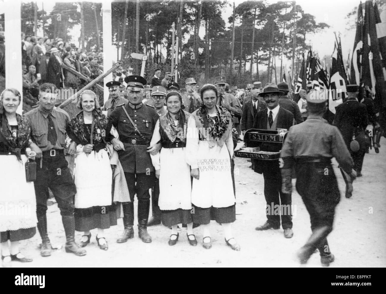 Nuremberg Rally 1933 in Nuremberg, Germany - Women in traditional costumes from Mecklenburg between members of the SA (Sturmabteilung), next to them a man selling cigarettes of the brand Salem. (Flaws in quality due to the historic picture copy) Fotoarchiv für Zeitgeschichtee - NO WIRE SERVICE – Stock Photo