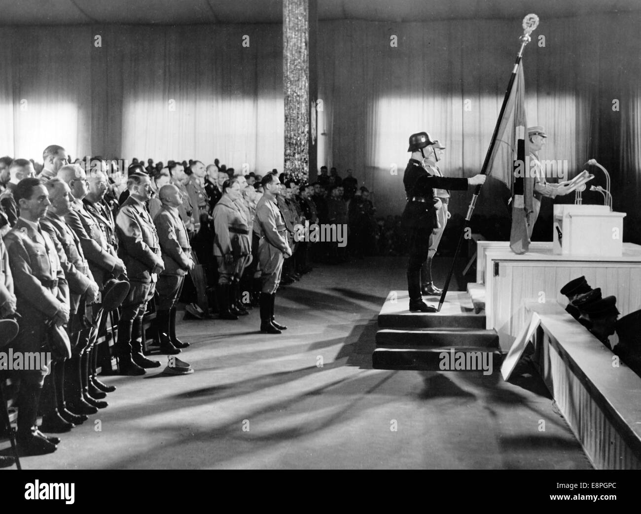 Nuremberg Rally 1936 in Nuremberg, Germany - Opening of the party congress at Luitpold Hall at the Nazi party rally grounds . Chief of staff of the Sturmabteilung (SA) Viktor Lutze reads out the names of the 'martyrs of the Beer Hall Putsch'. Behind him: Standartenfuehrer Jakob Grimminger holding the 'Blood Flag'. First Row L-R: Reich Minister Joseph Goebbels, Head of the German Labour Front Robert Ley, Reich Treasurer Franz Xaver Schwarz, Reichsfuehrer of the Schutzstaffel (SS) Heinrich Himmler, Adolf Hitler, Gauleiter Julius Streicher, Hermann Goering, Reich Minister Bernhard Rust. In fro Stock Photo