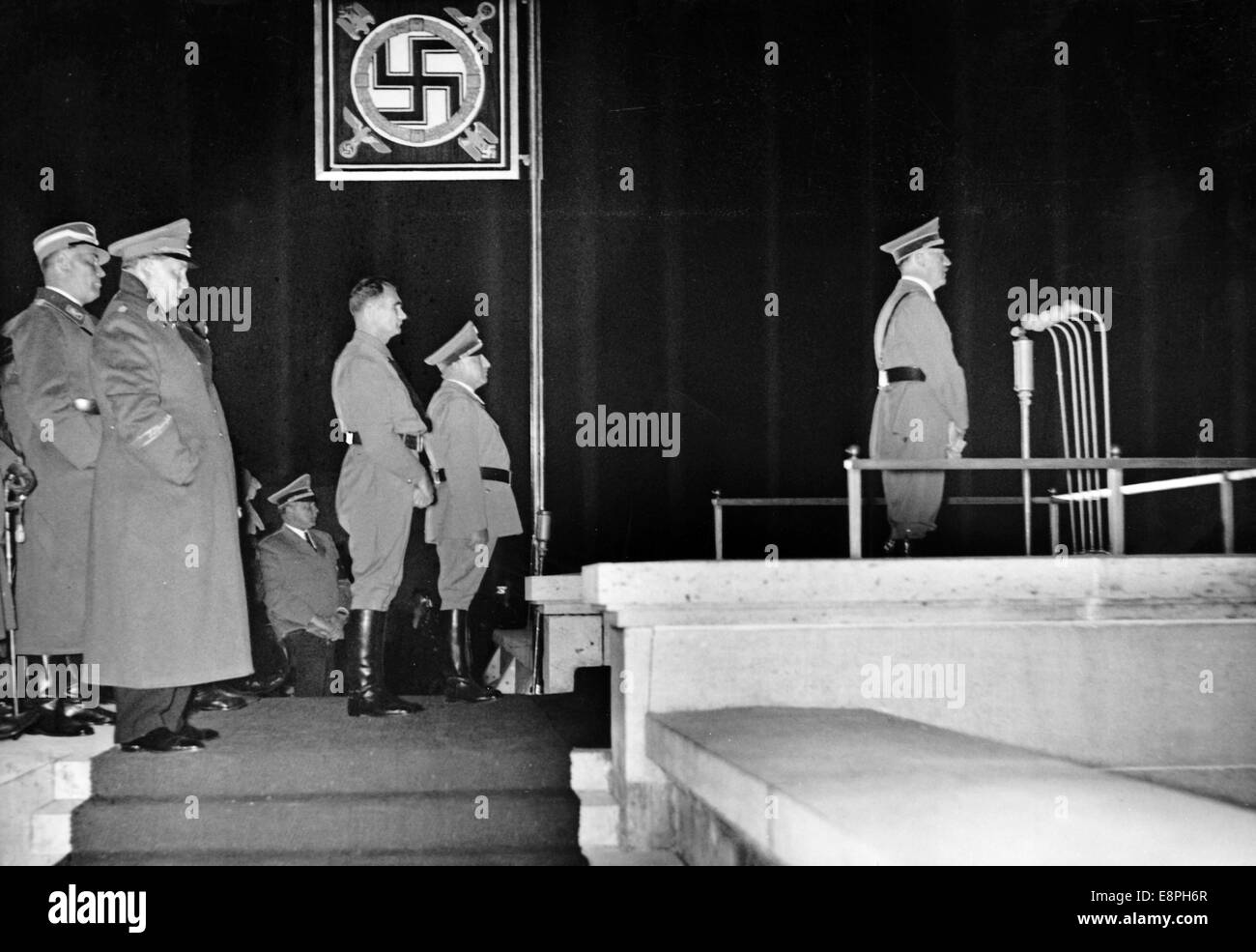 Nuremberg Rally 1937 in Nuremberg, Germany - Adolf Hitler holds a speech in an atmosphere created by searchlights in front of the political leaders of the NSDAP, 110,000 of whom - according to Nazi news reporting - have lined up for a roll call on Zeppelin Field at the Nazi party rally grounds. On the podium from right to left Adolf Hitler, head of the German Labour Front Robert Ley, Reich Minister Rudolf Hess, colonel general Hermann Goering and Hitler's chief adjutant Wilhelm Brueckner. (Flaws in quality due to the historic picture copy) Fotoarchiv für Zeitgeschichtee - NO WIRE SERVICE - Stock Photo